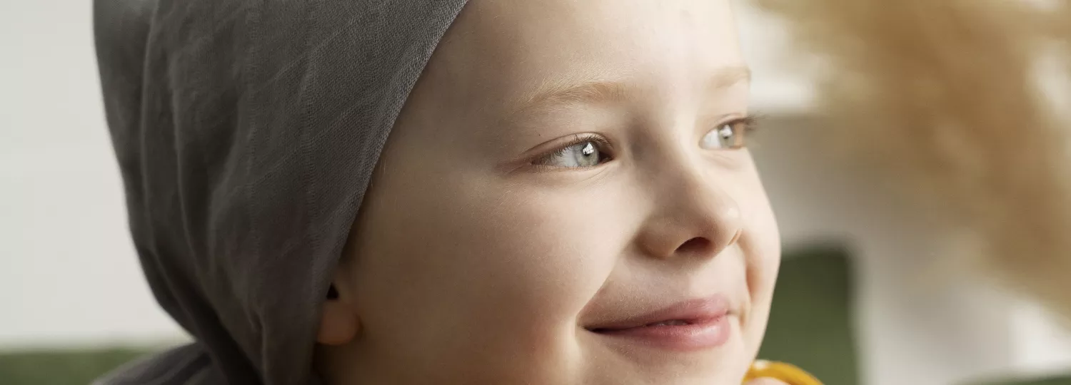 Photographie d'une petite fille avec un foulard gris sur la tête et portant un tee-shirt jaune